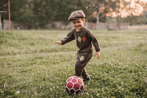 Photo a boy is playing football in the countryside the joyful childhood of the baby active sports