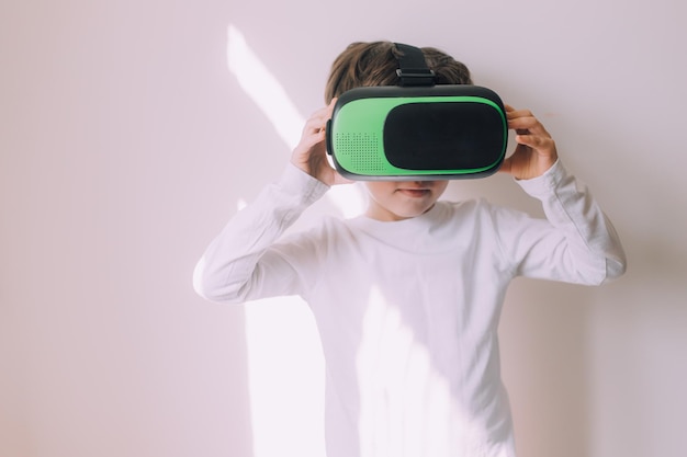 A boy is playing vr glasses on a white copyspace wall An article about modern gadgets An article about modern technologies