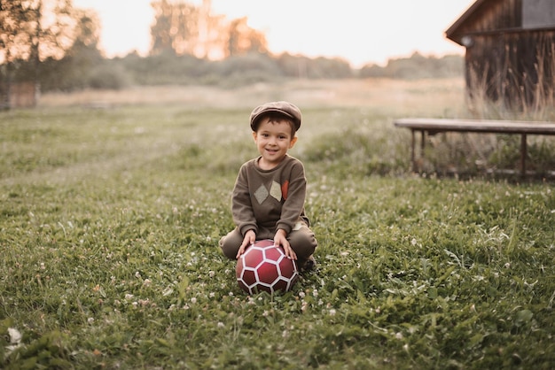 A boy is playing with a soccer ball in the fresh air in the countryside The boy's sincere smile Childhood in the fresh air