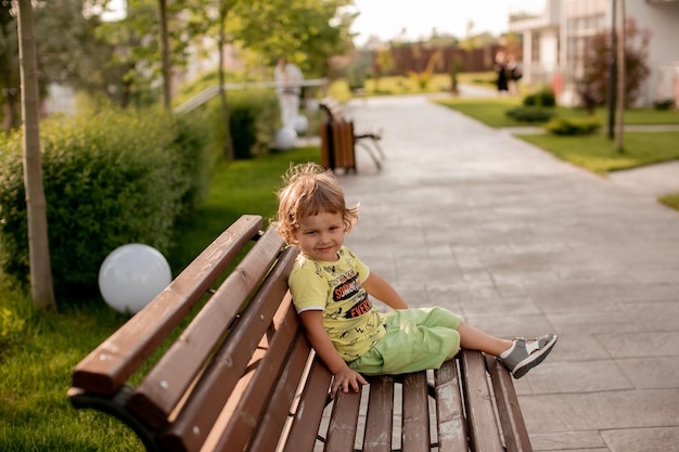 the boy is sitting alone on a bench