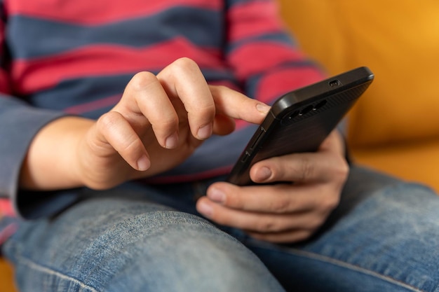 boy is sitting on the couch and using a smartphone