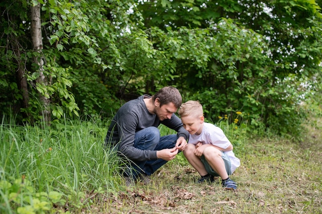 The boy is sitting next to his dad looking at the ground