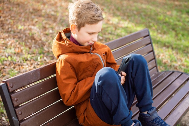 A boy is sitting with a phone on a bench