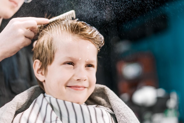 A boy is smiling while being splashed water in barbershop