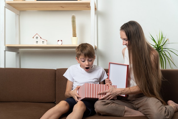 Boy is very surprised by gift. Mom gives gift to her son. Family holiday.