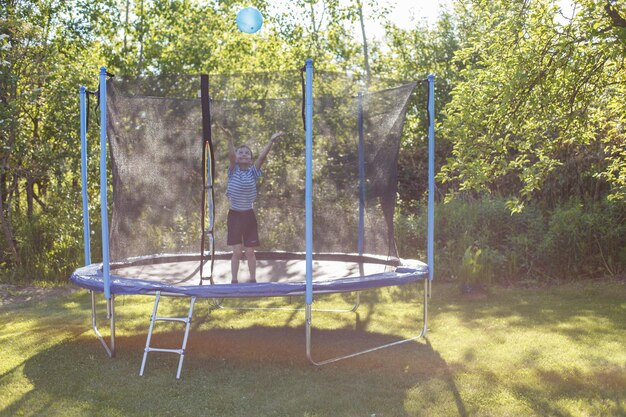 Boy jumping on trampoline child playing with a ball on a trampoline