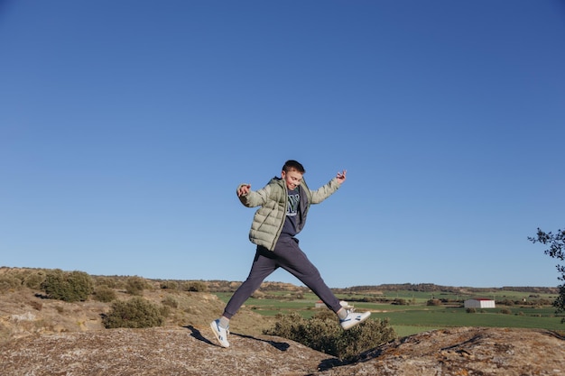 A boy jumps over a hill in the countryside