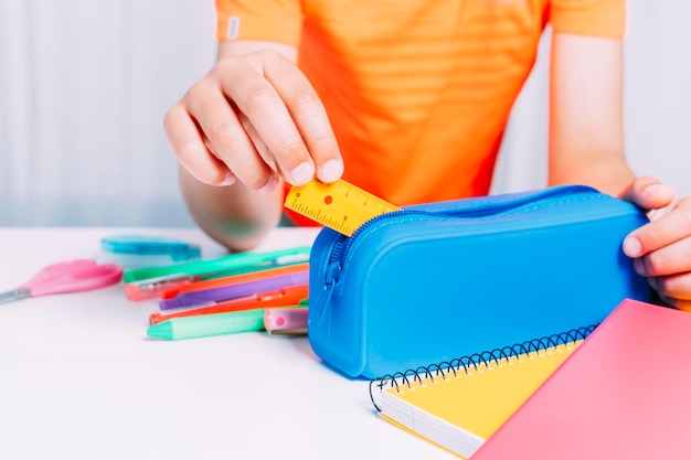 Boy keeping inside his blue pencil case all a small ruler pencils and scissors