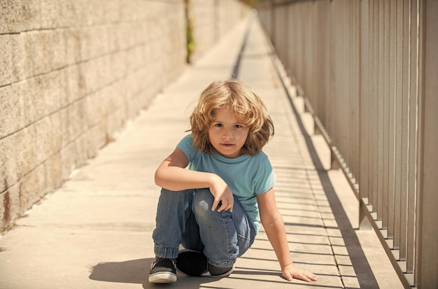 Boy kid take rest sitting down on promenade on summer outdoors resting