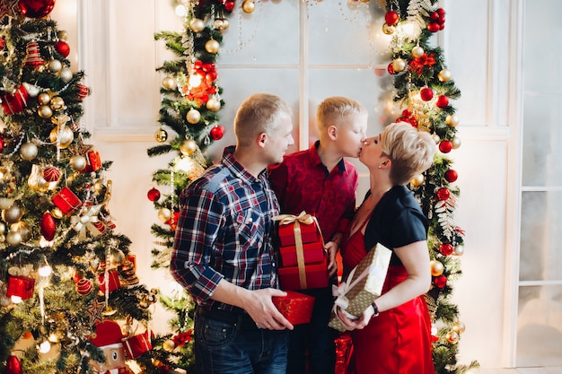 Boy kissing his mom while holding Christmas presents.