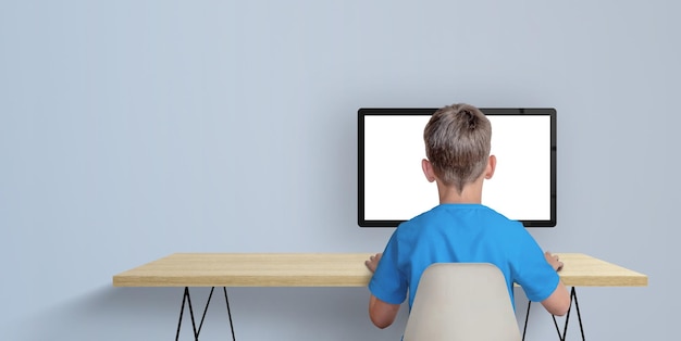 Boy learn to code on desktop computer concept A boy in a blue shirt with his back turned Copy space aside Isolated computer display for page promotion