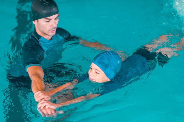 Photo boy learning to swim in pool with teacher