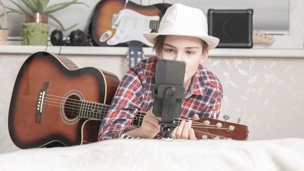 Boy learning or takes off the vlog to play guitar through a video call