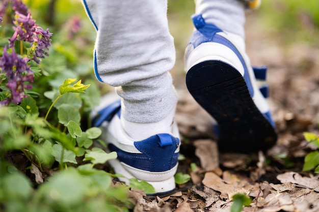 Boy legs wear sneakers walking on forest trail Outdoor spring leisure concept