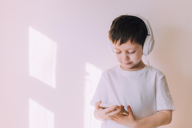 The boy listens to music with lifestyle headphones Modern technologies Kids and gadgets Music for children Modern children Smartphones in children