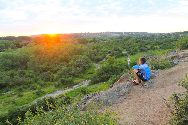 Boy looking to landscape in sunset