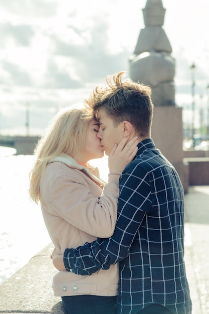 The boy looks tenderly at girl and wants to kiss. A young couple stands embracing