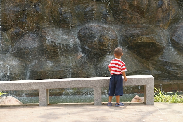 A boy looks at the waterfall in the garden