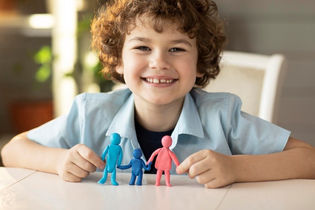 The boy made figures of people from plasticine dad mother and child happy smiles on camera