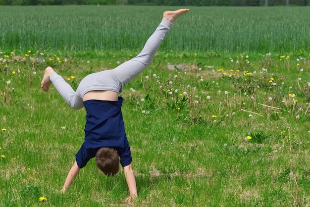 Boy makes an acrobatic wheel On the grass