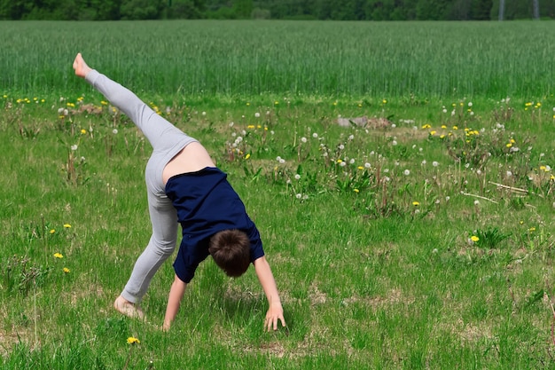 Boy makes an acrobatic wheel On the grass