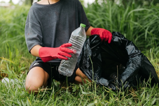 Boy man hand pick up plastic bottle in the forest. nature conservation and Environment concept.