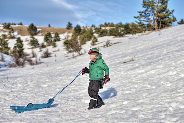 Boy in the mountains rides in the snow on a sled