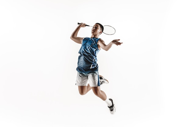 Boy playing badminton isolated on white wall.