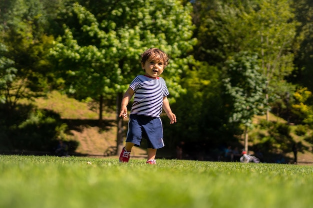 Boy playing ball in a park First step and already kicking the ball having fun