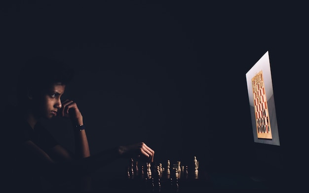 A boy playing chess against a computer