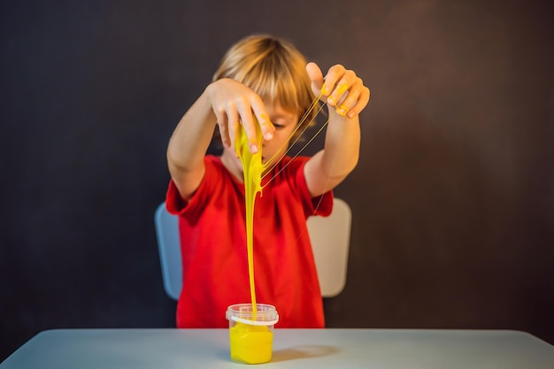 Boy playing hand made toy called slime child play with slime kid squeeze and stretching slime