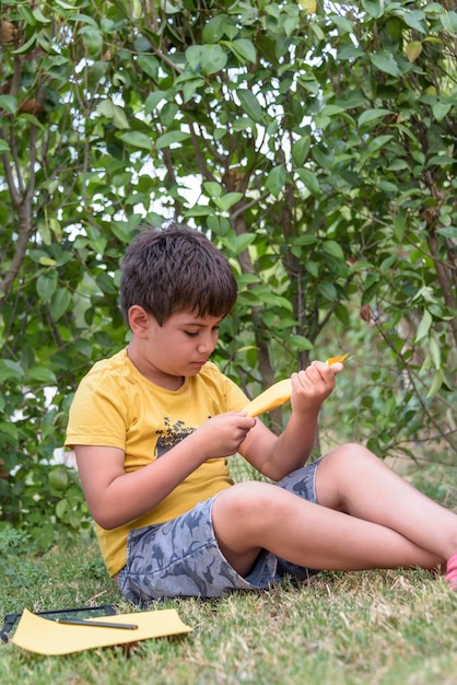 Boy playing toss paper plane outdoors looking away Portrait of a cheerful caucasian boy playing in the spring and summer park having fun on the weekend