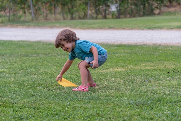 Boy playing toss paper plane outdoors looking away Portrait of a cheerful caucasian boy playing in the spring and summer park having fun on the weekend