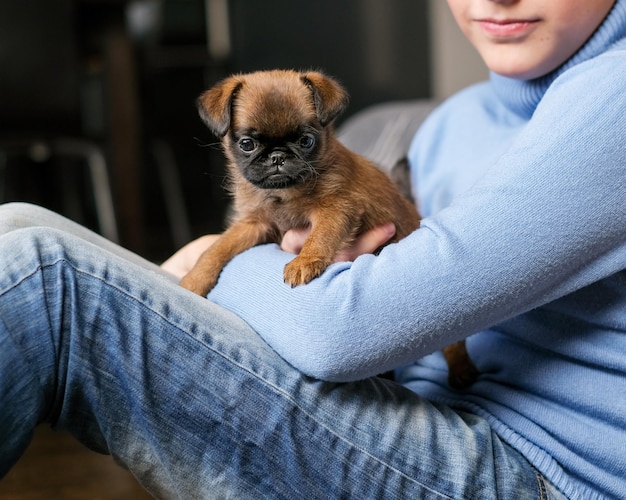 Boy playing with baby dog. Kid play with puppy at home. Little boy and griffon or brabanson dog