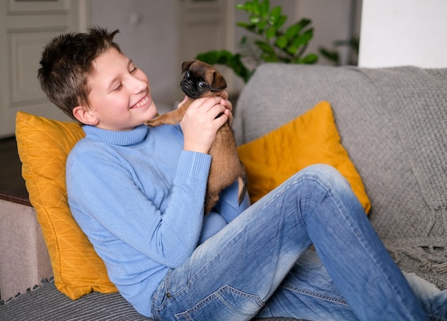 Boy playing with baby dog. Kid play with puppy at home. Little boy and griffon or brabanson dog