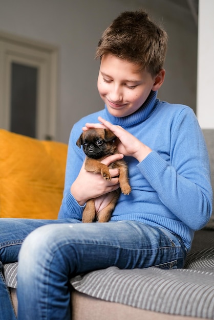 Boy playing with baby dog. Kid play with puppy at home. Little boy and griffon or brabanson dog