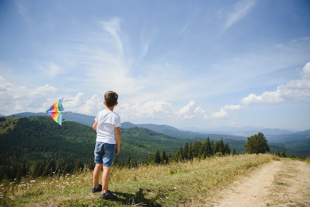 Boy playing with a kite in the mountains