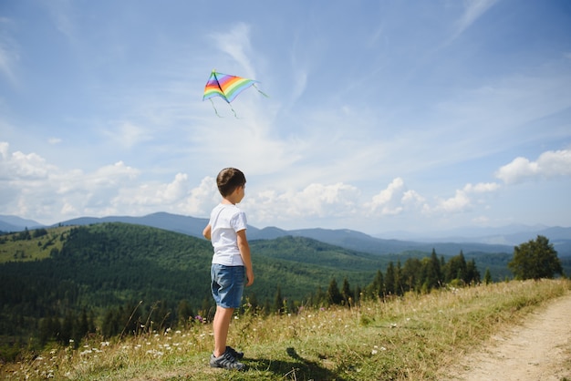 Boy playing with a kite in the mountains