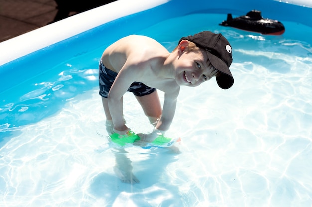 A boy plays in the pool with a water pistol Its a very sunny day