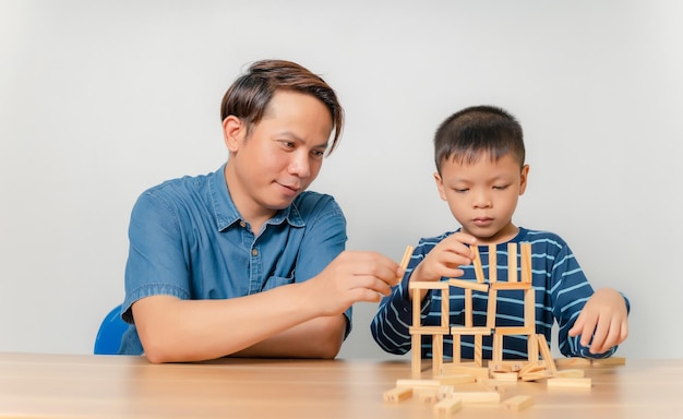 A boy plays with his father at home with a wooden puzzle