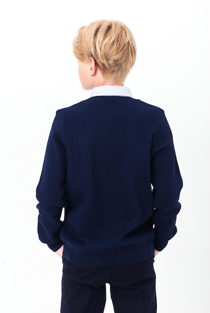 The boy poses in a school uniform a shirt and a jacket on a white background A teenager stands with his back to the camera Vertical photo