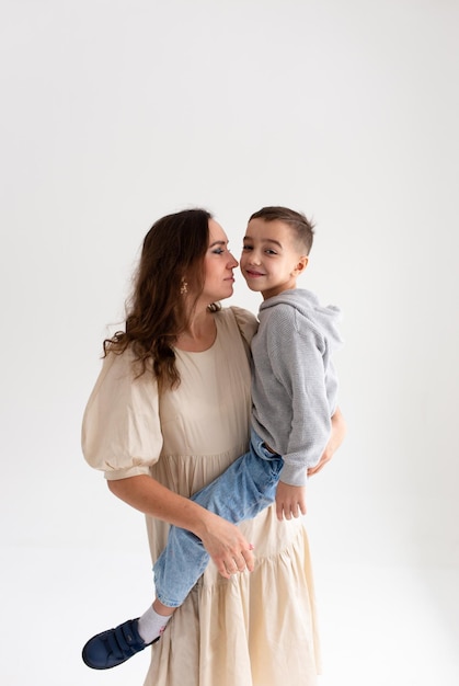 Boy preschooler and mother smile and hug on gray background in photo studio