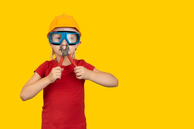 Boy in protective helmet and goggles holding in hands pliers