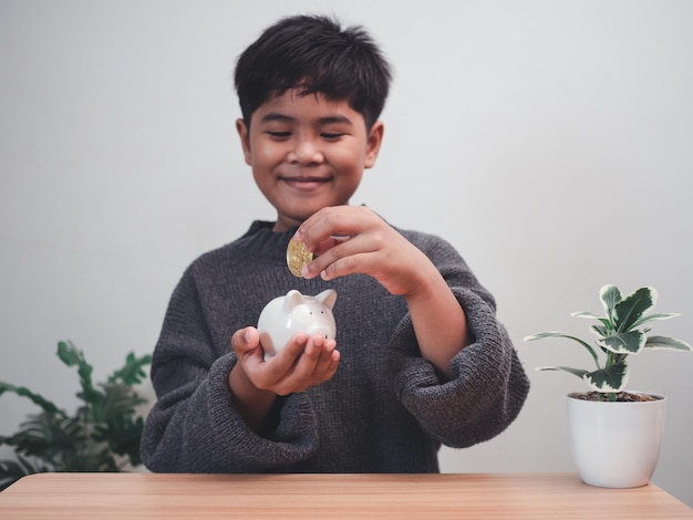 A boy putting coins into piggy bank Learning financial responsibility