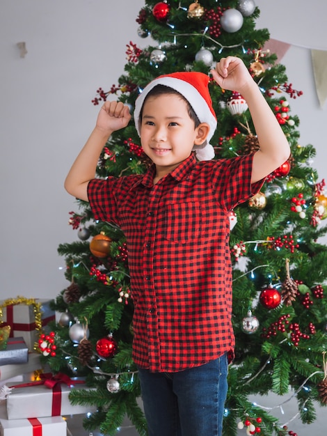 Boy in a red shirt is happy and funny to celebrate Christmas with christmas tree