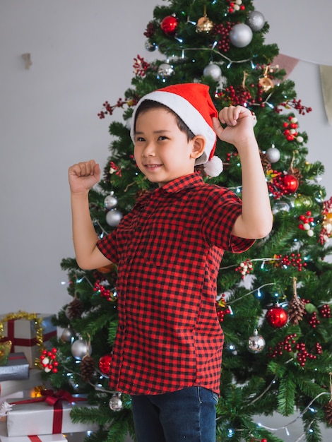 Boy in a red shirt is happy and funny to celebrate Christmas with christmas tree