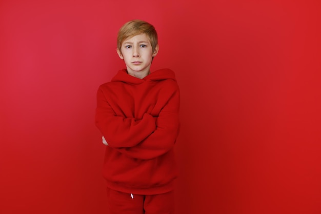 A boy in a red suit folded his hands in front of him and shows they are contentment