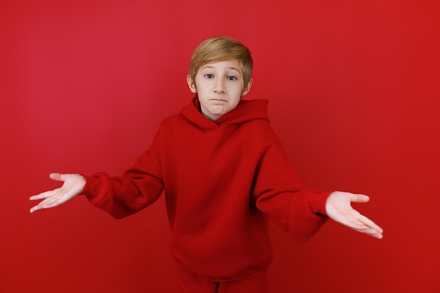 A boy in a red tracksuit spread his arms to the sides