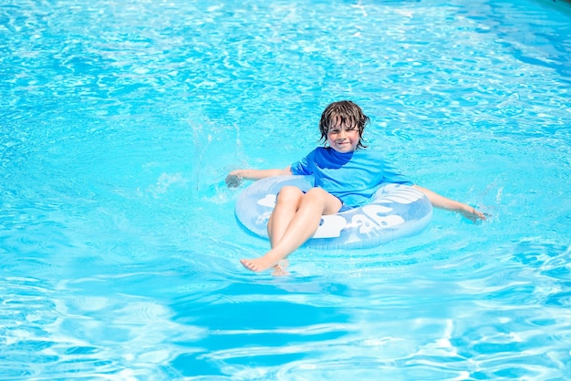 Boy relaxing on an inflatable swim ring in a sunny day spending time in a swimming pool aquapark resort hotel Summer holidays concept