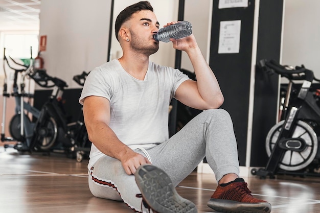 Boy resting while hydrating in gym